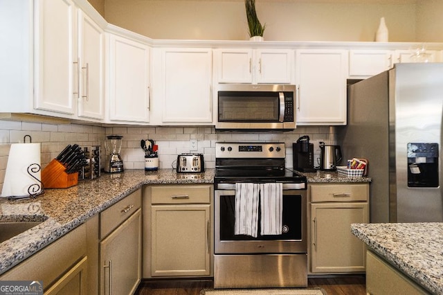 kitchen with light stone counters, white cabinetry, stainless steel appliances, and decorative backsplash