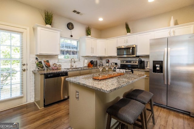 kitchen featuring sink, backsplash, stainless steel appliances, white cabinets, and a kitchen island