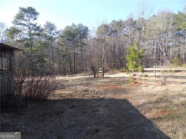 view of yard featuring a forest view and fence