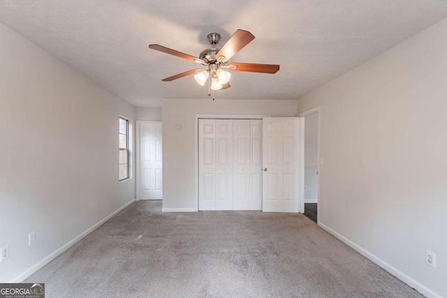 unfurnished bedroom featuring ceiling fan, light colored carpet, a closet, and a textured ceiling