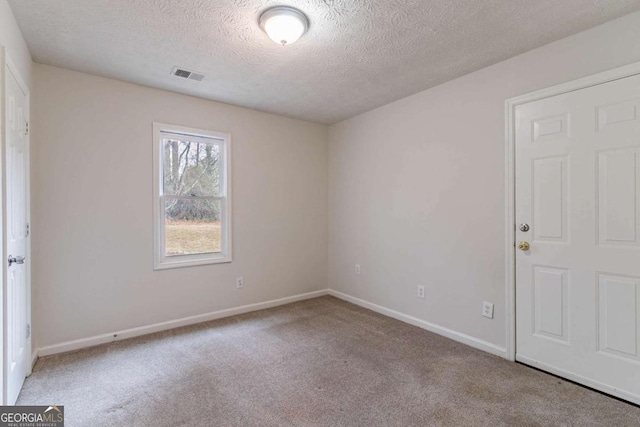 carpeted spare room featuring a textured ceiling