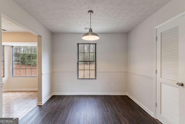 unfurnished room featuring dark hardwood / wood-style flooring, plenty of natural light, and a textured ceiling