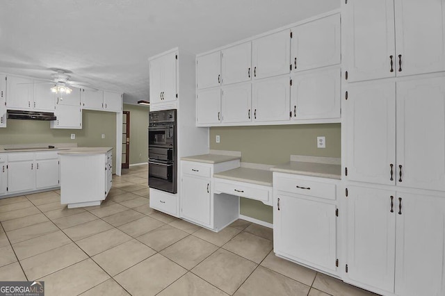 kitchen with light tile patterned floors, ceiling fan, black appliances, white cabinets, and a kitchen island