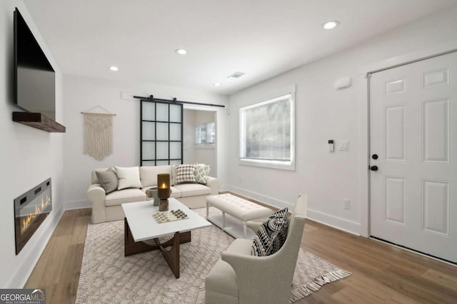 living room with a barn door and light hardwood / wood-style flooring