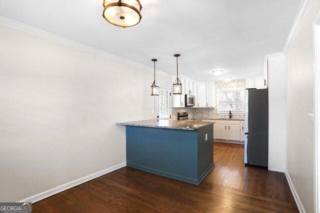 kitchen with kitchen peninsula, appliances with stainless steel finishes, dark stone countertops, white cabinets, and decorative backsplash