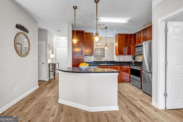 kitchen featuring decorative light fixtures, light hardwood / wood-style flooring, a textured ceiling, appliances with stainless steel finishes, and decorative backsplash