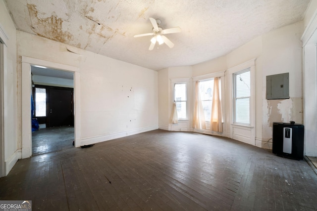 unfurnished living room featuring dark wood-type flooring, ceiling fan, plenty of natural light, and electric panel