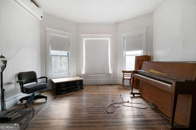 living area with a textured ceiling, dark hardwood / wood-style floors, and a wall mounted AC