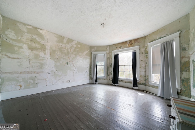 unfurnished room with hardwood / wood-style flooring and a textured ceiling