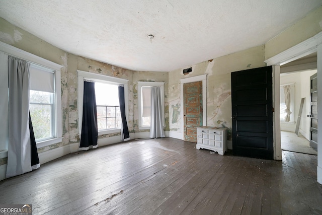 unfurnished living room featuring dark hardwood / wood-style flooring and a textured ceiling