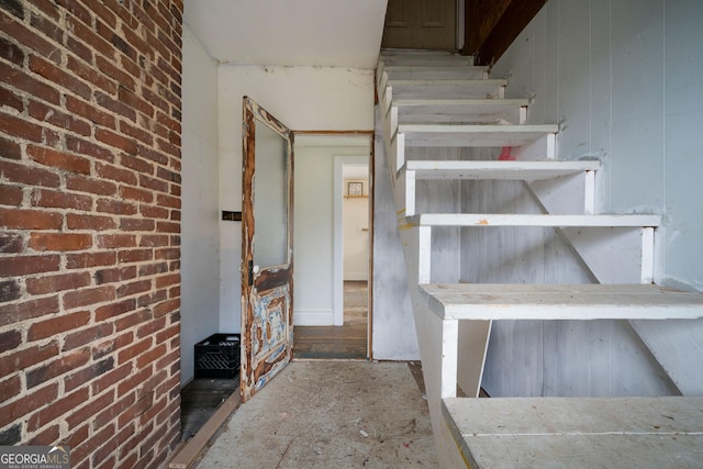 stairway featuring brick wall