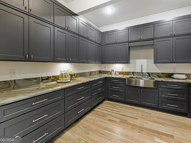 kitchen with light stone countertops, sink, and light wood-type flooring