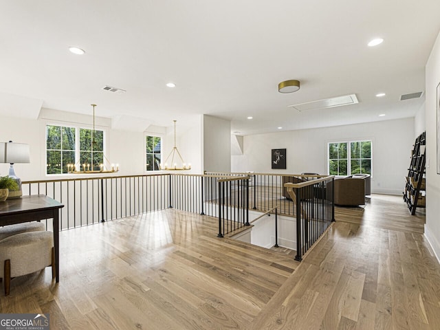 corridor featuring a notable chandelier and light hardwood / wood-style flooring