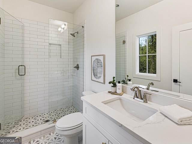 bathroom featuring vanity, toilet, and a shower with shower door