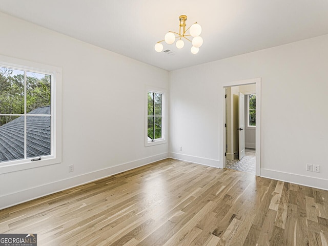 empty room featuring light hardwood / wood-style floors and a notable chandelier