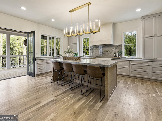 kitchen featuring light stone counters, a kitchen bar, gray cabinets, and a kitchen island