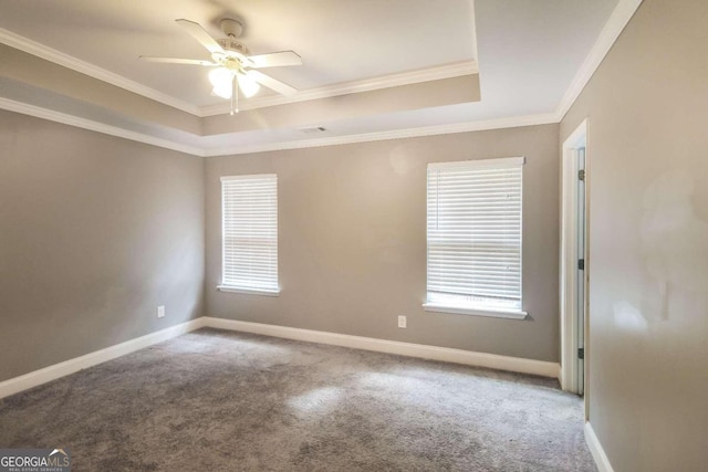 carpeted empty room with ceiling fan, ornamental molding, and a raised ceiling