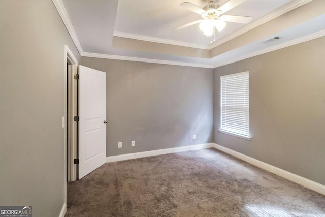 carpeted spare room featuring a tray ceiling, ornamental molding, and ceiling fan