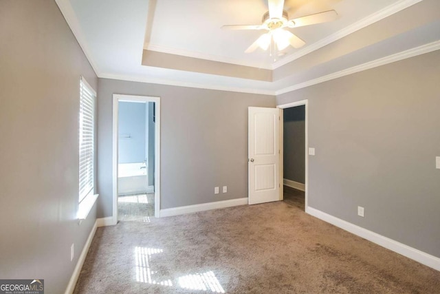 unfurnished bedroom featuring crown molding, a tray ceiling, carpet floors, and multiple windows