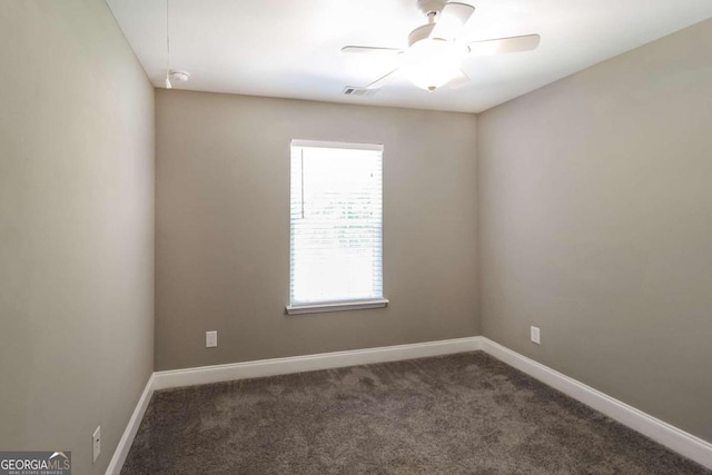 empty room with ceiling fan and dark colored carpet