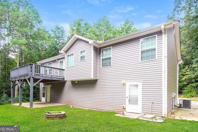 rear view of house featuring central AC, an outdoor fire pit, and a lawn