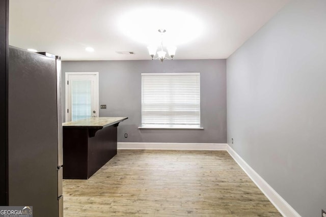 unfurnished dining area featuring a chandelier and light hardwood / wood-style flooring