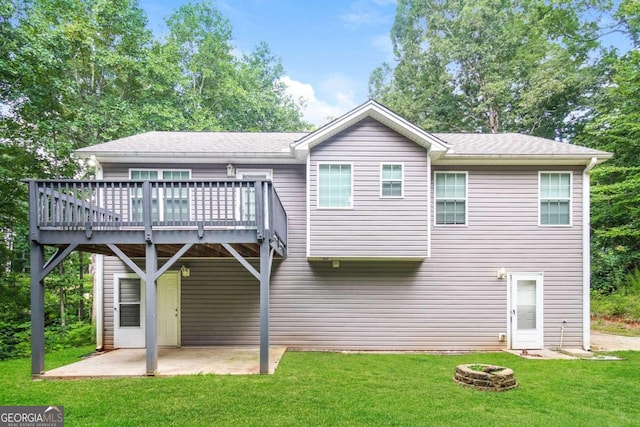 back of property with a wooden deck, a yard, a patio, and an outdoor fire pit