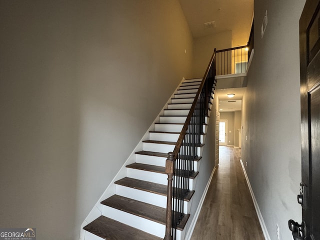 stairs with a high ceiling and wood-type flooring