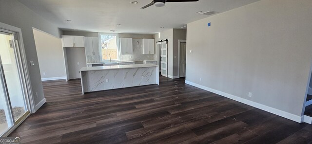 kitchen featuring white cabinetry, dark hardwood / wood-style floors, tasteful backsplash, a kitchen island, and a barn door