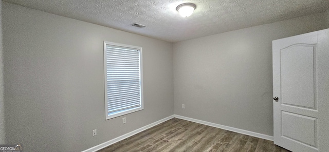 empty room featuring hardwood / wood-style flooring and a textured ceiling