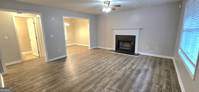 unfurnished living room featuring ceiling fan, a healthy amount of sunlight, a textured ceiling, and dark hardwood / wood-style flooring