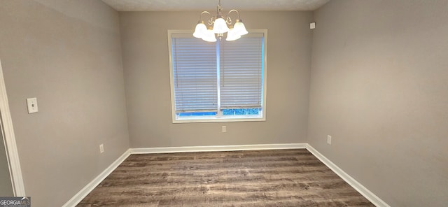 empty room featuring dark hardwood / wood-style floors and an inviting chandelier