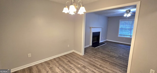 unfurnished living room featuring ceiling fan with notable chandelier and dark hardwood / wood-style floors