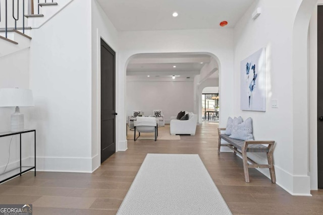 interior space featuring wood finished floors, recessed lighting, stairway, arched walkways, and baseboards