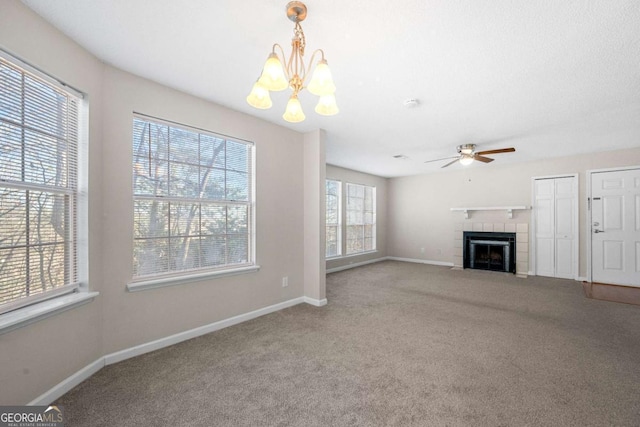 unfurnished living room featuring ceiling fan with notable chandelier, a tile fireplace, and carpet