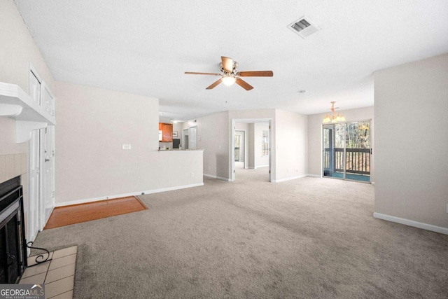 unfurnished living room with light carpet, ceiling fan with notable chandelier, and a tile fireplace