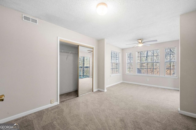 unfurnished bedroom featuring a closet, light carpet, and a textured ceiling