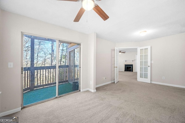 carpeted spare room featuring ceiling fan and french doors