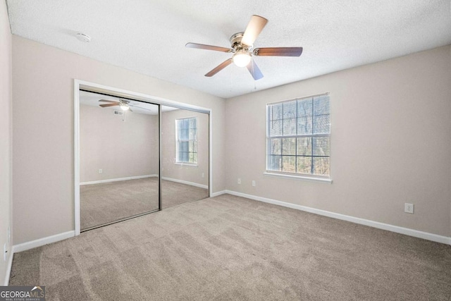 unfurnished bedroom with ceiling fan, carpet flooring, a textured ceiling, and a closet