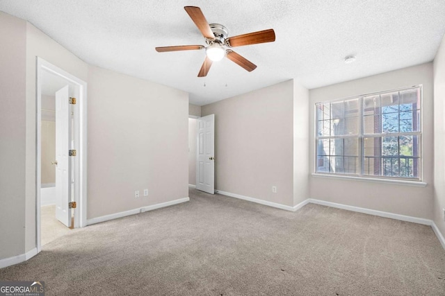 unfurnished bedroom with ensuite bathroom, light colored carpet, ceiling fan, and a textured ceiling