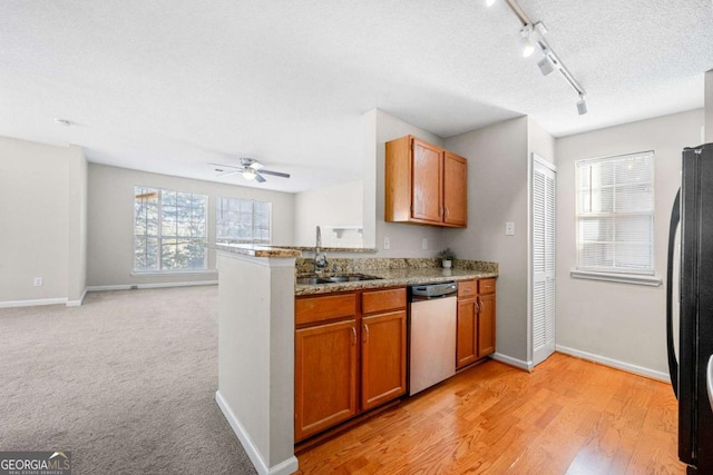 kitchen featuring sink, a textured ceiling, black refrigerator, stainless steel dishwasher, and kitchen peninsula