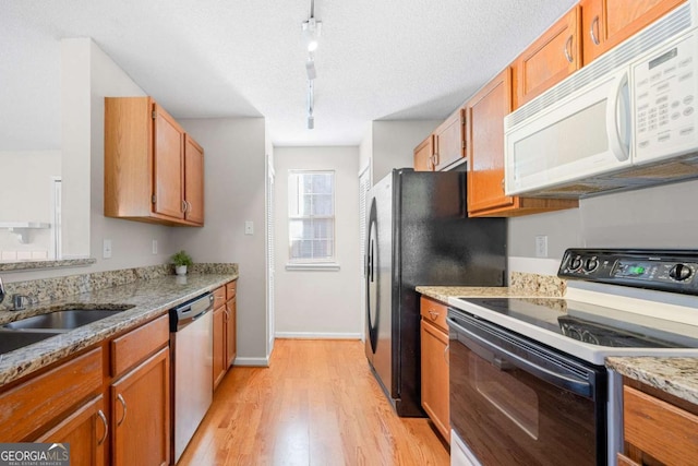 kitchen with a textured ceiling, electric range, stainless steel dishwasher, light stone countertops, and light hardwood / wood-style floors