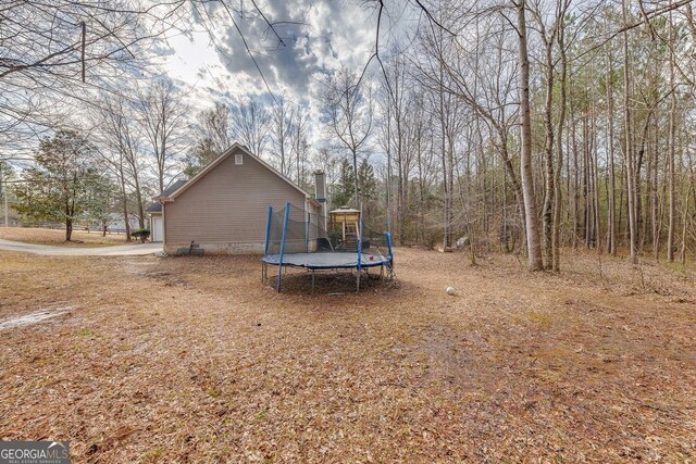 5833 Westerling Pl, Powder Springs, GA 30127 - view of property exterior featuring a trampoline, a chimney, and an attached garage