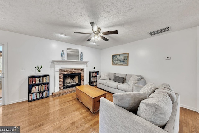 5833 Westerling Pl, Powder Springs, GA 30127 - living room with a ceiling fan, a fireplace, light wood finished floors, a textured ceiling, and baseboards