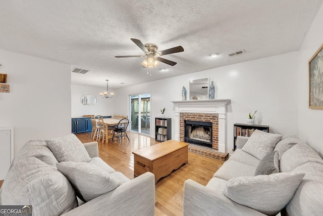 5833 Westerling Pl, Powder Springs, GA 30127 - living room with ceiling fan, a textured ceiling, light wood-type flooring, a fireplace, and a chandelier
