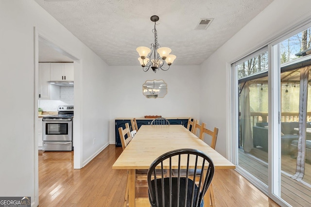5833 Westerling Pl, Powder Springs, GA 30127 - dining space featuring a chandelier, light wood-style floors, a textured ceiling, and baseboards