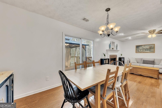 5833 Westerling Pl, Powder Springs, GA 30127 - dining area featuring light wood-type flooring, baseboards, a textured ceiling, ceiling fan, and a brick fireplace