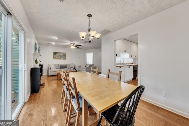 5833 Westerling Pl, Powder Springs, GA 30127 - dining space featuring a chandelier, light wood finished floors, baseboards, ceiling fan, and a textured ceiling