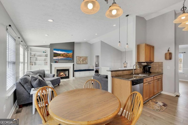 dining room with sink, light hardwood / wood-style flooring, high vaulted ceiling, and a textured ceiling