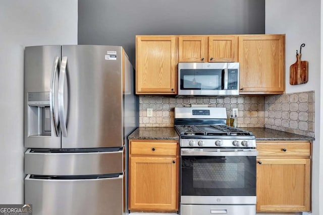 kitchen with stainless steel appliances, dark stone countertops, backsplash, and light brown cabinets